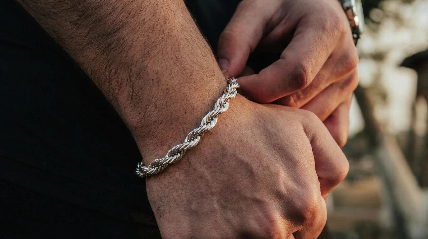 Photo - Close-up of a man adjusting a silver chain bracelet on his wrist, illustrating how should a chain bracelet fit with a comfortable snug position